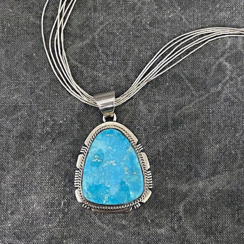 Turquoise pendant hanging on a six strand and sterling silver necklace