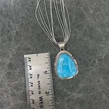 Load image into Gallery viewer, Turquoise pendant hanging on a six strand and sterling silver necklace next to ruler showing size of pendant
