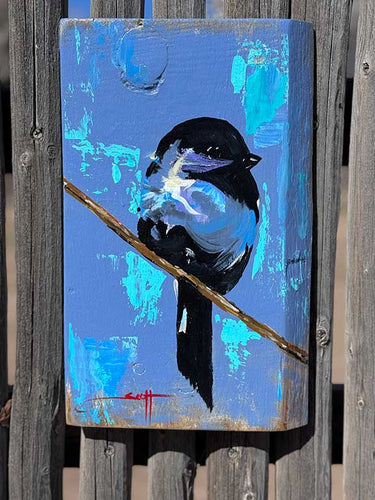 A painting of a black and blue bird perched on a branch against a wooden background.